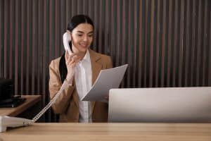 Receptionist talking on phone at countertop in hotel