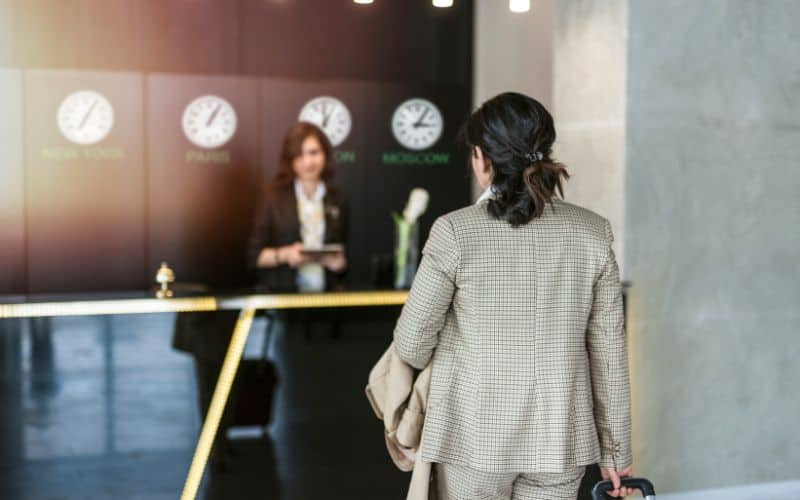 Business woman approaching hotel font desk to ask for a room