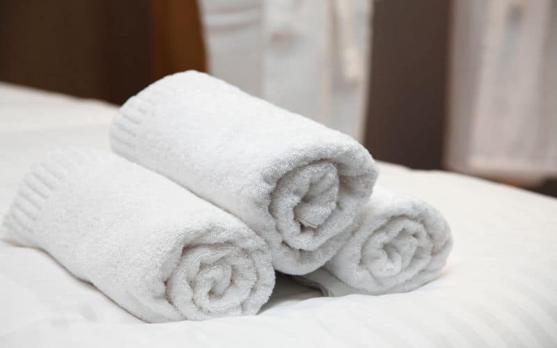Hotel towels rolled up on bed