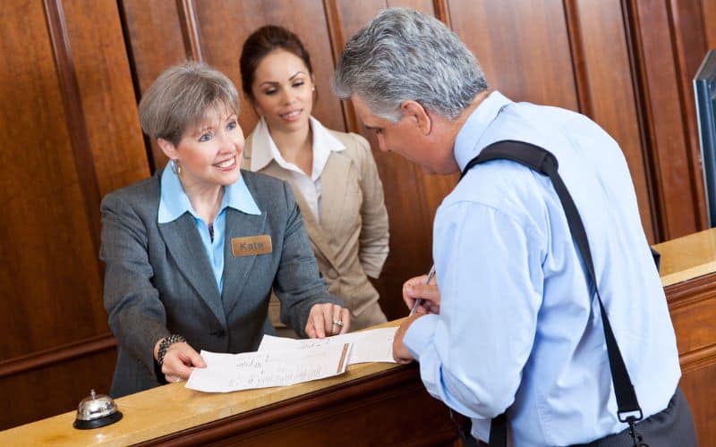 Font desk staff showing hotel bill to guest