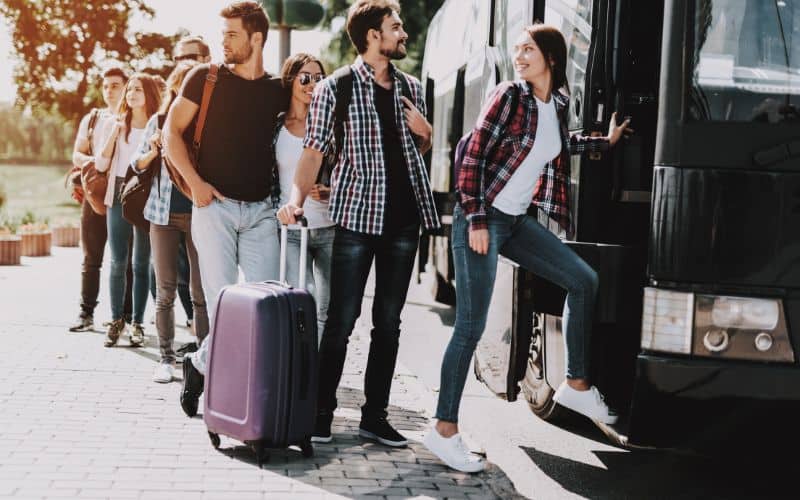 Group of young travellers boarding on bus