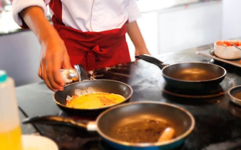 Chef adding salt to scrambled eggs