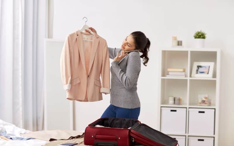 Woman calling the hotel and packing travel bag