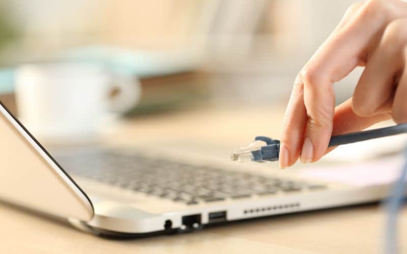 Woman hand plugging ethernet cable on laptop